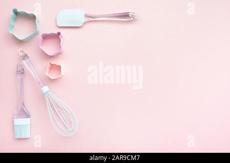 Mix backing utensils as a whisk, spatula, cooking brush on pink background with copy space, top view Stock Photo