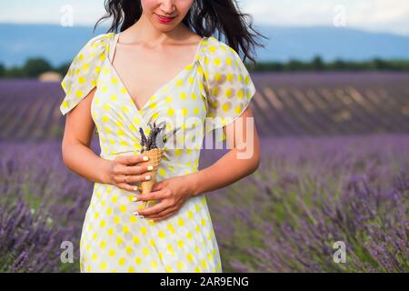 Young woman is standing with lavender flowers in a waffle cup holding in a hand.