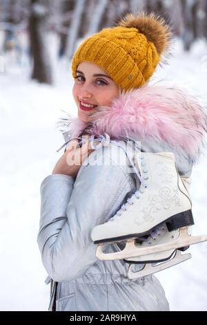 Close up portrait of a young beautiful girl with ice skates go to the rink, winter outdoors Stock Photo