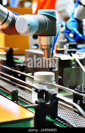 Robot arm arranged glass water bottle on Automatic industrial machinery equipment in production line factory Stock Photo
