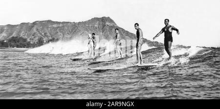 Vintage panoramic water view of surfers riding a wave together at Waikiki with Diamond Head in the background. Stock Photo