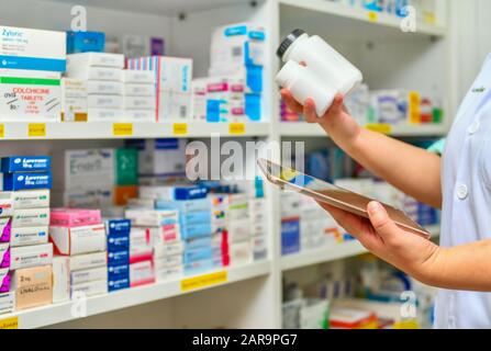 Pharmacist holding medicine bottle and computer tablet for filling prescription in pharmacy drugstore. Stock Photo