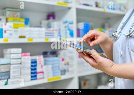 Doctor using computer tablet for search bar on display in pharmacy drugstore shelves background.Online medical concept. Stock Photo