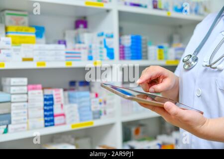 Doctor using computer tablet for search bar on display in pharmacy drugstore shelves background.Online medical concept. Stock Photo