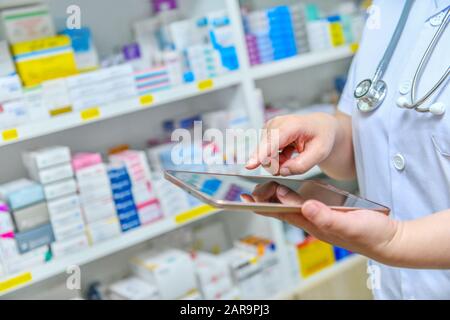 Doctor using computer tablet for search bar on display in pharmacy drugstore shelves background.Online medical concept. Stock Photo