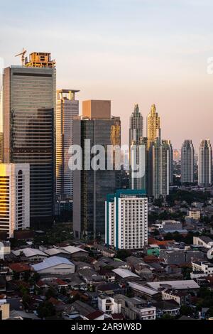 Sunset over Jakarta skyline where modern luxury condo and office towers contrast with low rise residential district in  downtown Jakarta, Indonesia ca Stock Photo