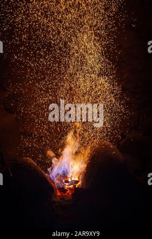 Burning red hot sparks fly from big fire. Abstract dark background Stock Photo