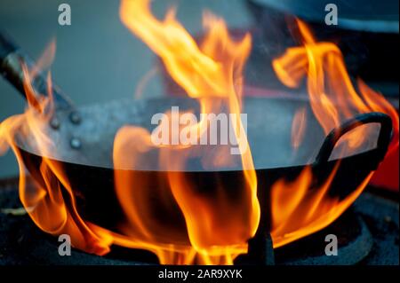 Chef cooking with fire in frying pan on street Stock Photo