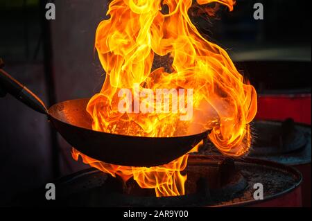 Chef cooking with fire in frying pan on street Stock Photo