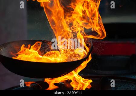 Chef cooking with fire in frying pan on street Stock Photo