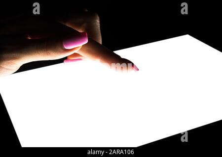 Tablet computer mockup in woman hand isolated on black background. Tablet laptop mockup with blank white screen at night. Empty space for text. Copy s Stock Photo