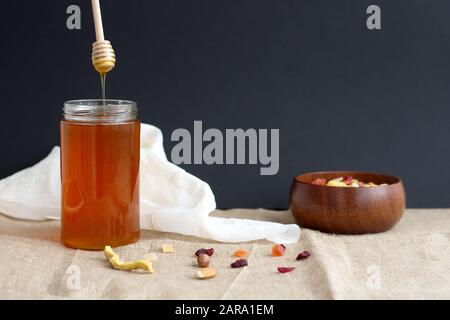 Honey in glass container and dried fruits in wooden bowl Stock Photo