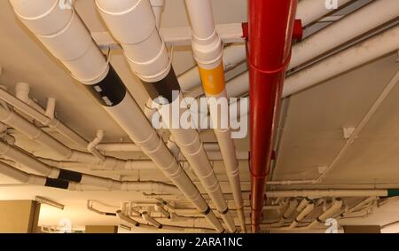 Water distribution system pipes installed by hanging from ceiling, selective focus, the red pipe will be used during fire fighting Stock Photo