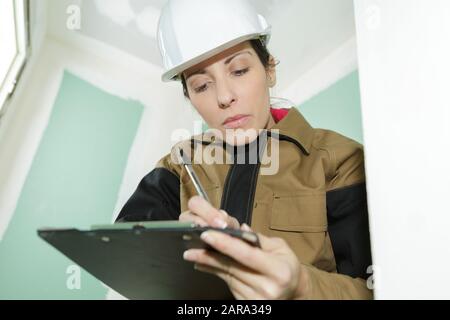 female contractor on indoor site making notes on clipboard Stock Photo