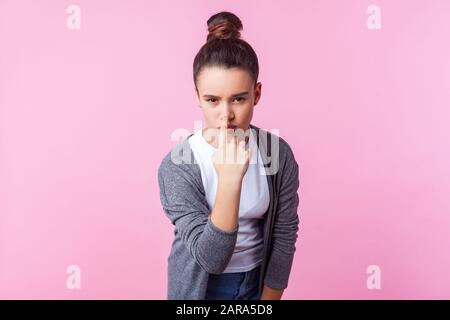 You are liar! Portrait of cute brunette teenage girl with bun hairstyle in casual clothes touching nose with finger showing lie gesture, expressing di Stock Photo