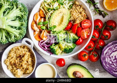 Buddha bowl salad with quinoa, avocado, broccoli, sweet potato and tahini dressing, gray background. Stock Photo