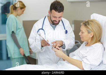 patient in hospital bed signing consent form Stock Photo