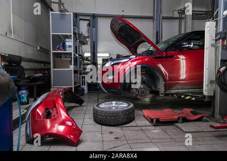 A used car raised on a lift for repair and under it a detached engine ...