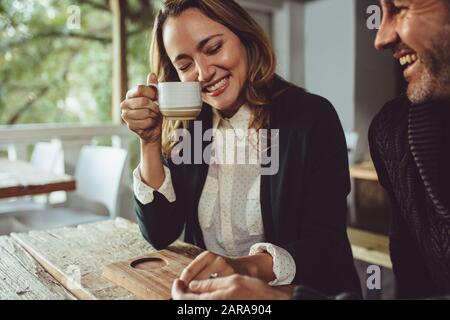 Smiling man and woman sitting at coffee shop having coffee. Loving couple sitting at a cafe. Stock Photo