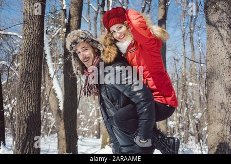 Man carrying his woman piggyback on a winter day Stock Photo