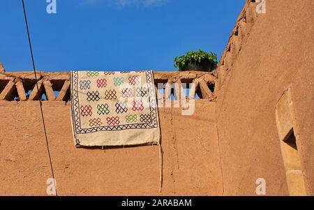 Colorful handmade Persian carpet hangs over the walls of a mud house Stock Photo