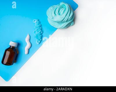 Components to make slime. Child education concept. On blue surface slime, toothpaste, shaving foam, Sodium tetraborate decahydrate Stock Photo