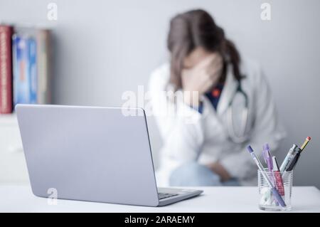 Tired Young Woman Doctor Working with a Laptop in a Clinic Stock Photo