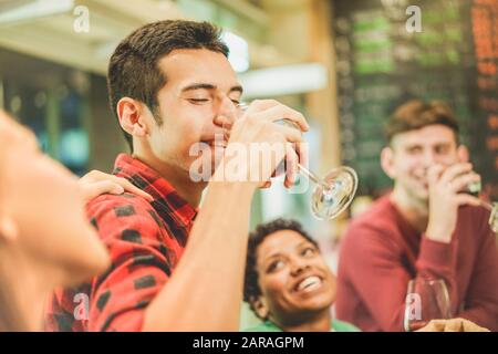 Group of cheerful students toasting red wine at wine cocktail bar - Young people drinking pre dinner aperitif - Friendship concept with people enjoyin Stock Photo