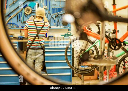 Owner bike mechanic preparing racing bicycles in workshop - Young trendy man checking new carbon fiber superbike indoor - Professional maintenance con Stock Photo