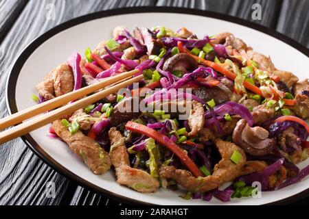 Traditional Chinese fried pork moo shu with vegetables and mushrooms close-up in a plate on the table. horizontal Stock Photo
