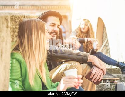 Young students drinking coffee in paper ripley cup outdoor during a university break - Cheerful friends toasting cappuccino in old town center - Focus Stock Photo