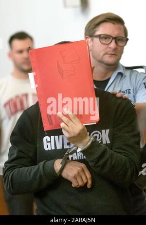 Dortmund, Germany. 27th Jan, 2020. The accused (M) is led in handcuffs into the courtroom of the regional court. Six months after a woman's body was found in a suitcase, the 24-year-old ex-partner of the victim is on trial. The public prosecutor's office accuses the man of having first strangled his former partner in the argument and then killed her with 76 stab wounds. Afterwards he is said to have stowed the body in a suitcase and parked it near an S-Bahn station. Credit: Bernd Thissen/dpa/Alamy Live News Stock Photo