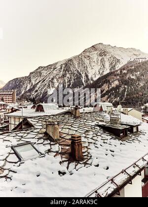 Courmayeur, Italy - January 18, 2020 Landscape of the snowy mountains of the Aosta Valley of Italy from the roofs of the snowy houses during the day Stock Photo