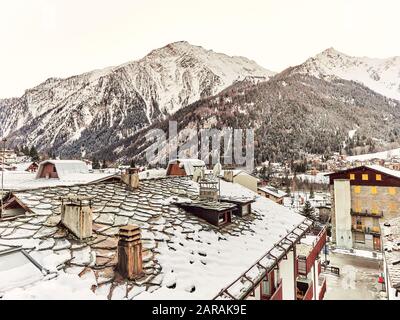 Courmayeur, Italy - January 18, 2020 Landscape of the snowy mountains of the Aosta Valley of Italy from the roofs of the snowy houses during the day Stock Photo
