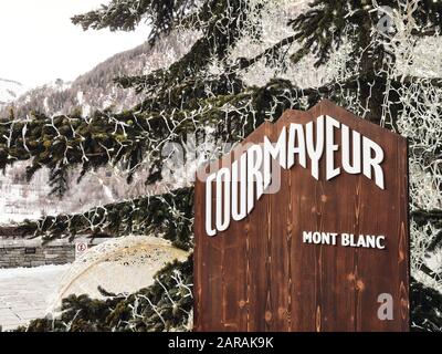 Courmayeur, Italy - January 18, 2020 View of the wooden ad with white letters of the village of Courmayour in the Aosta Valley of Italy in front of th Stock Photo