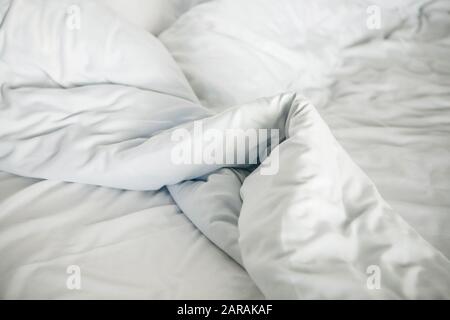 Crumpled white blanket on the bed after sleeping in the morning Stock Photo