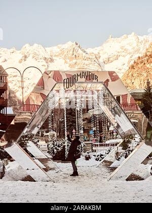 Courmayeur, Italy - January 18, 2020 Unrecognizable person takes a selfie in Courmayeur square with the background of snowy mountains Stock Photo