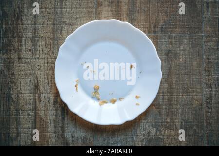 Empty white plate with crumbs on a wooden surface Stock Photo