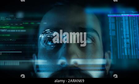 Close up of a young man eye controlling a futuristic computer system. Computer programmer coding on futuristic holographic display. Stock Photo
