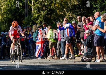 Female Polish road racing cyclist riding uphill, competing in cycle race, cheered & clapped by supporters - UCI World Championships, Harrogate, GB, UK Stock Photo