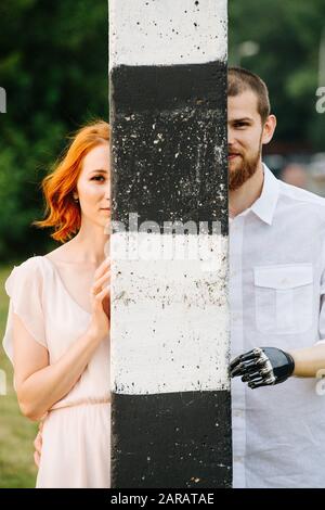 Couple peeking from behind a post, half of each in hidden Stock Photo