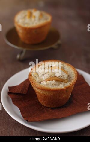 Two pear friands, small almond cakes, over brown papper and white plate Stock Photo