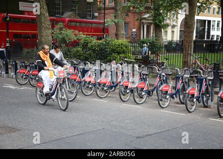 LONDON, UK - JULY 7, 2016: People ride Santander Cycles bicycle hire station in Soho, London, UK. The public bike hire network has 839 stations and 13 Stock Photo