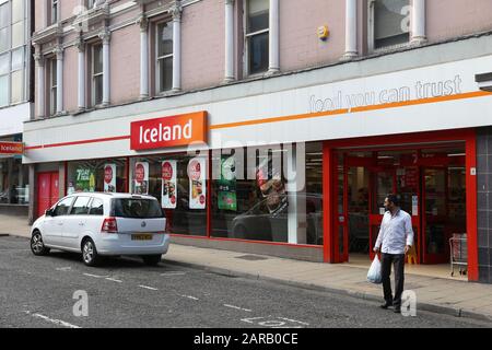 BARNSLEY, UK - JULY 10, 2016: Man exits Iceland store in Barnsley, UK. The frozen foods company Iceland has 814 stores in the UK. Stock Photo