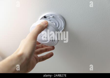 hand installing smoke detector on the room ceiling