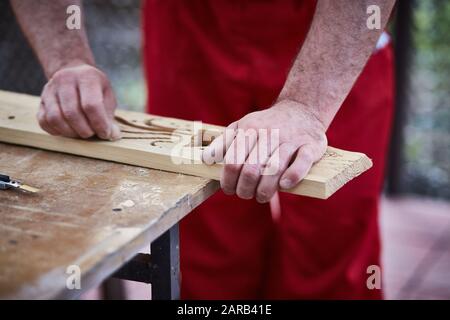 Closeup of male hands carpenter using sandpaper to sand wooden detail Stock Photo