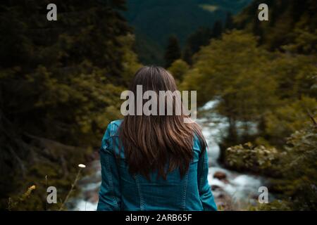 Rear view of young woman looking out towards the stream on the stream Stock Photo