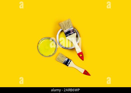 Renovation picture. Yellow background with one paint can and two brushes. Flat lay, top view, copy space. Stock Photo