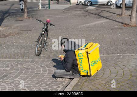 Rome, 17/01/2020: young boy glovo rider  working in the so called gig economy, having lunch, Esquilino square. ©Andrea Sabbadini Stock Photo