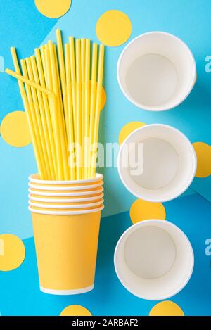 Yellow straws for a party in paper cups on a bright blue background Stock Photo